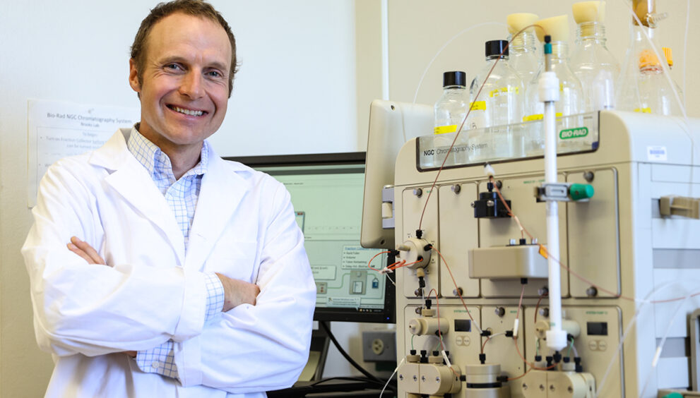 Faculty member smiling and posing in front of science equipment